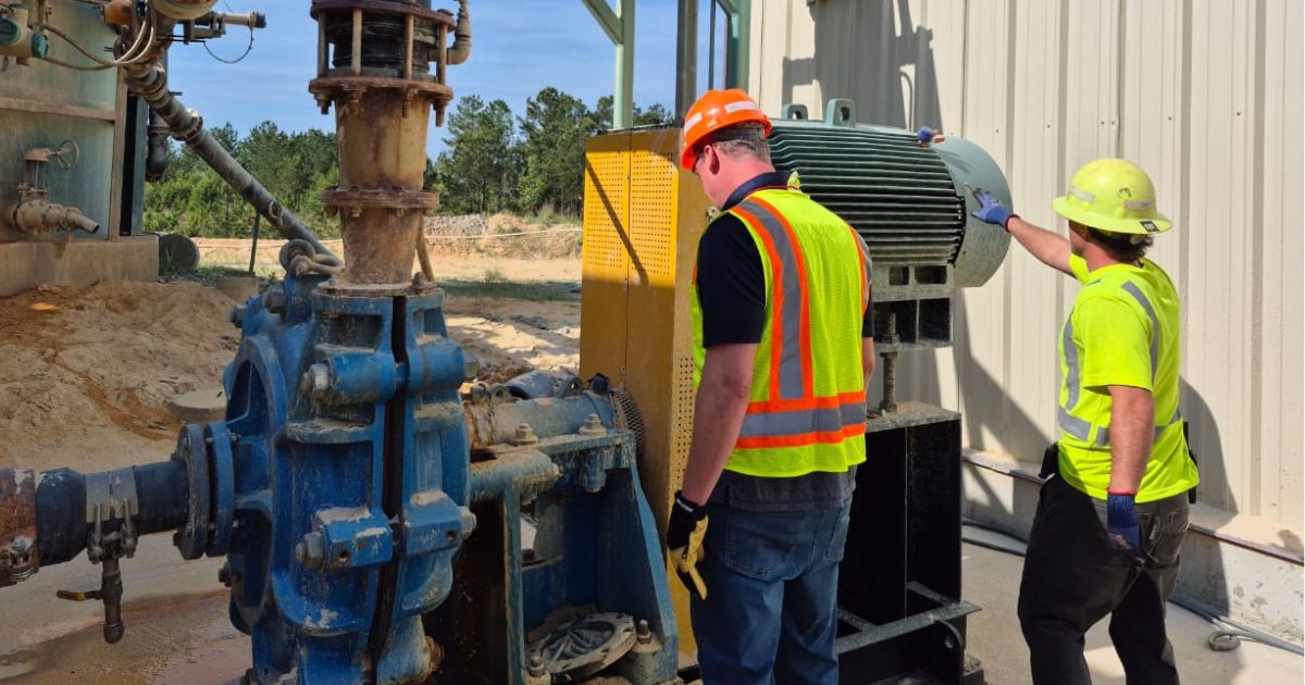 Técnicos inspeccionando una bomba para lodos y su motor en una instalación industrial.